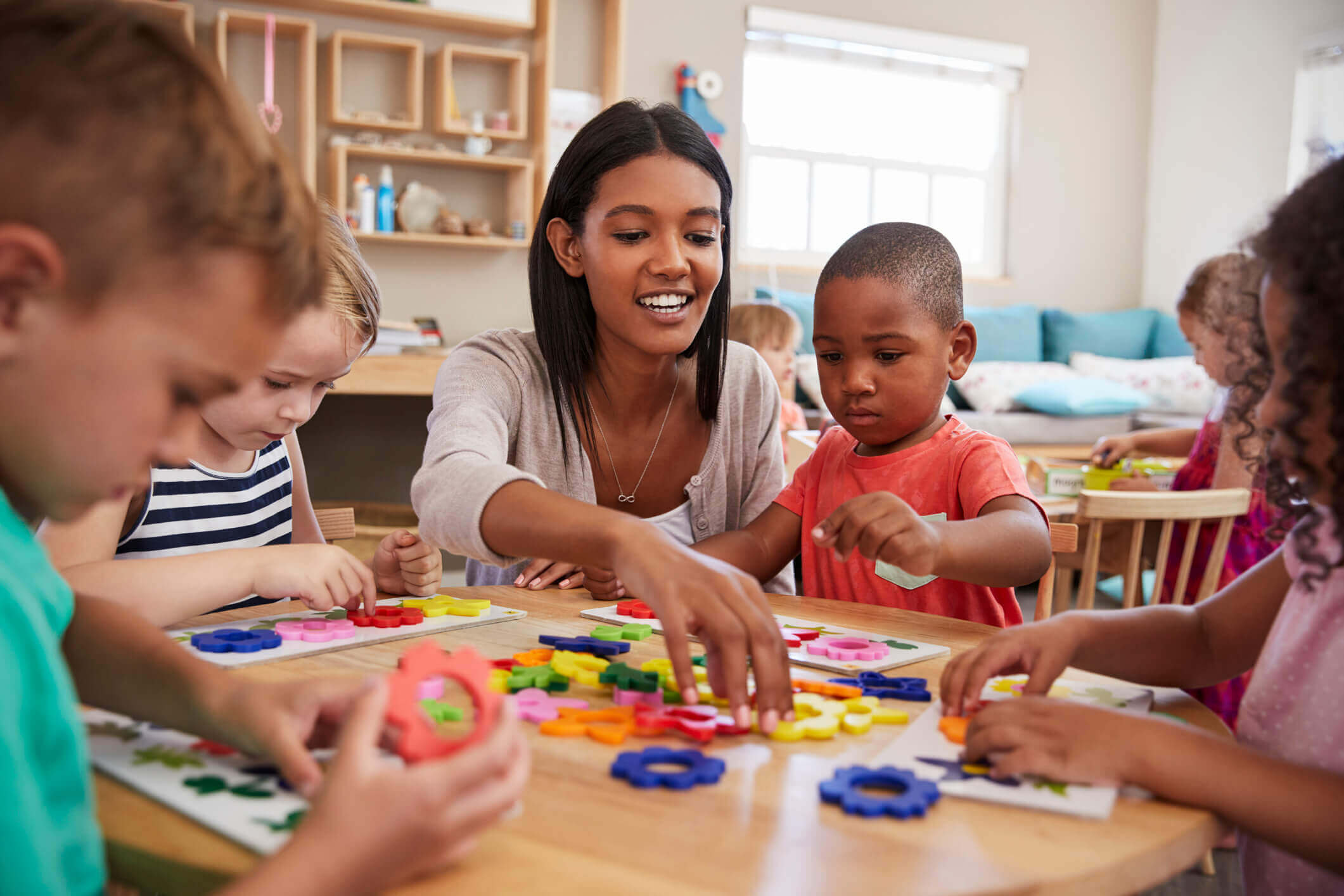 A teacher helping children with colorful puzzles at a table